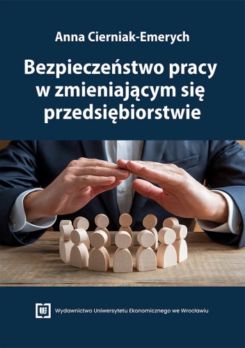 Okładka książki na granatowym tle. U góry nazwisko autorki i tytuł. Pośrodku dłonie osoby w garniturze osłaniające grupę drewnianych figurek symbolizujących pracowników. Na dole logo wydawnictwa.